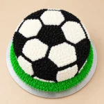 Football theme cake with black-and-white soccer ball decoration and green grass frosting by SJ Cake Art